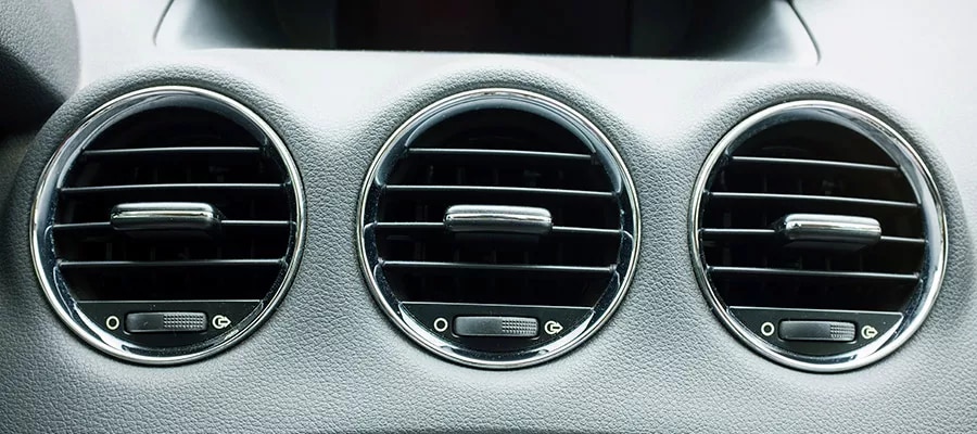 Three round air-conditioning vents on a car dashboard