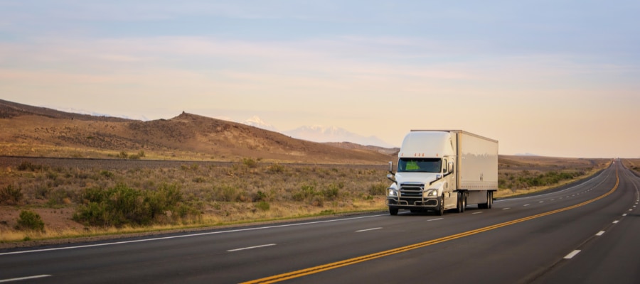 White refrigerated transport truck travelling on a rural road